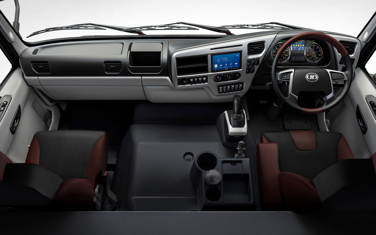 Truck cabin interior with two seats, steering wheel, dashboard, and gear lever.
