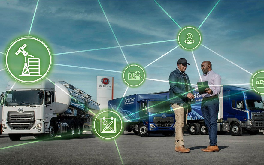 Two men shake hands near trucks, connected by digital network icons under a blue sky.