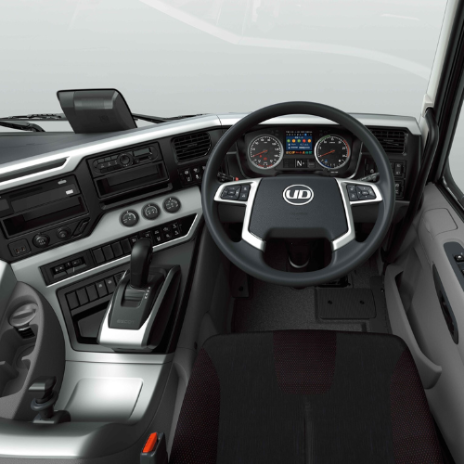 Modern truck cabin dashboard with steering wheel, gear lever, and digital displays.