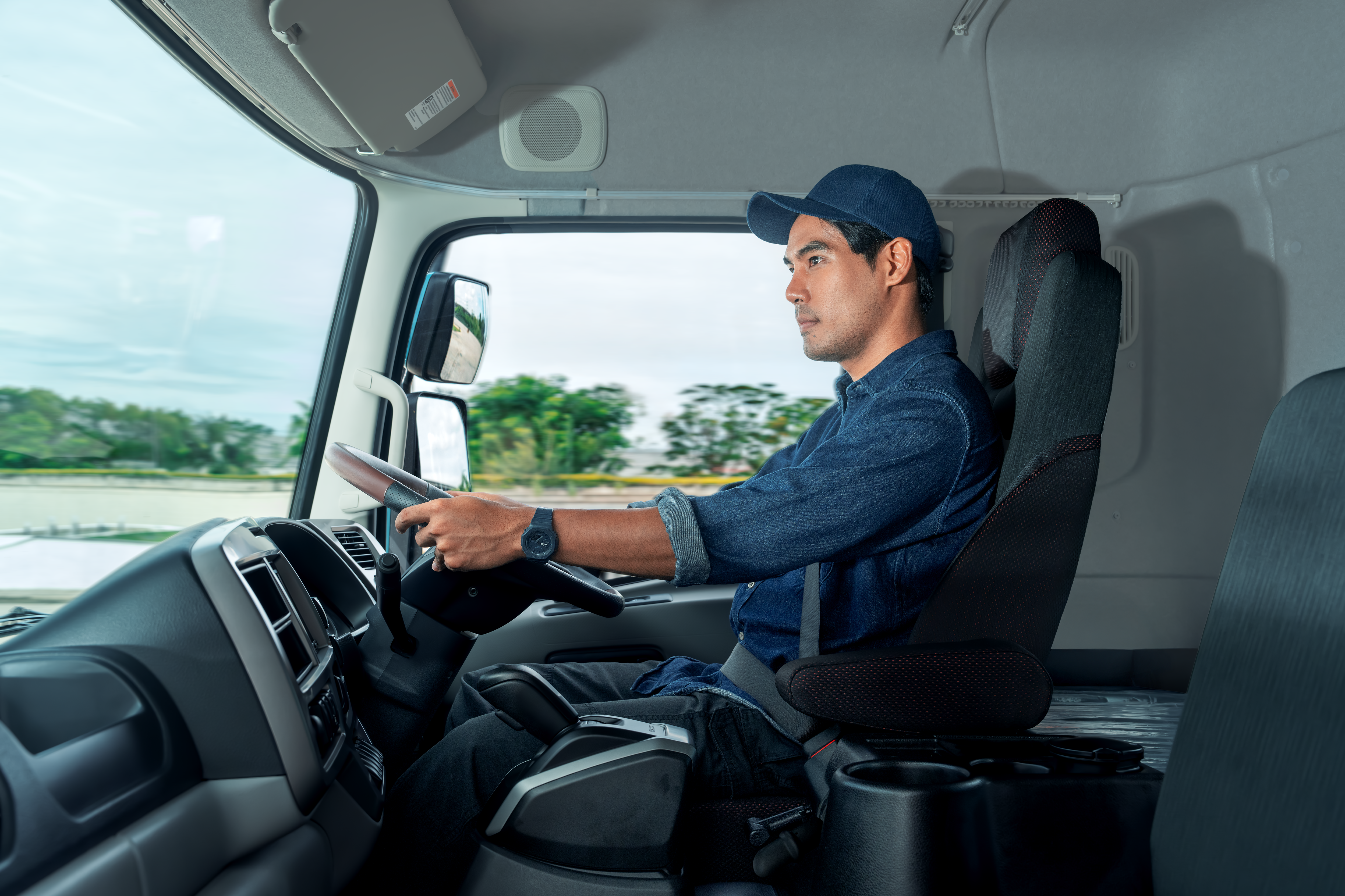 Man wearing a cap driving a truck Quester in daylight.