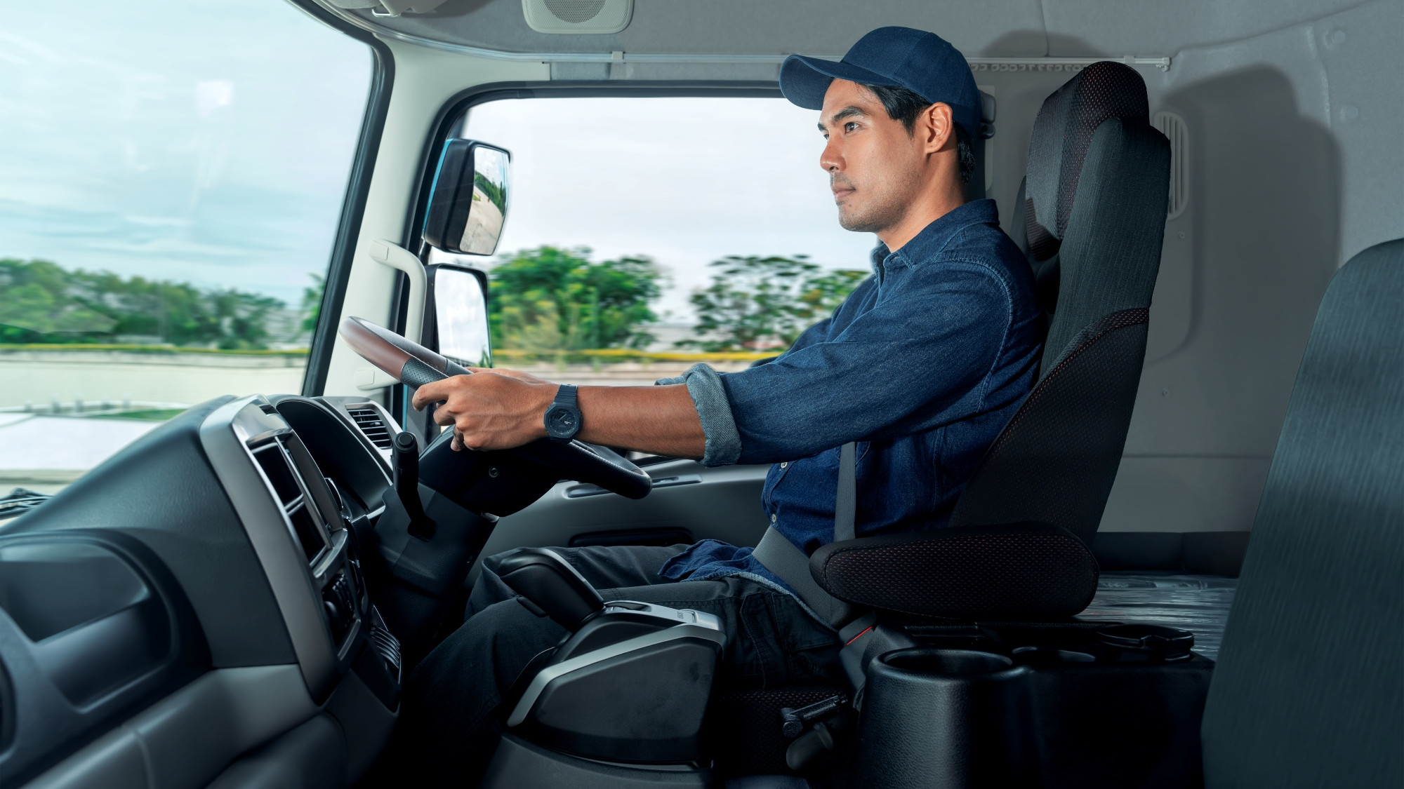 Mtu aliyevaa kofia na shati la buluu akiendesha lori.