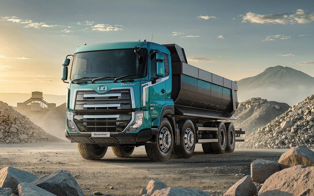 Blue dump truck parked at a rocky construction site during sunrise.
