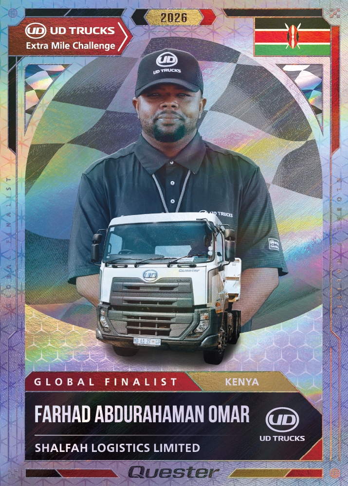 Man in a black cap and polo shirt stands behind a white truck with a Kenyan flag above.