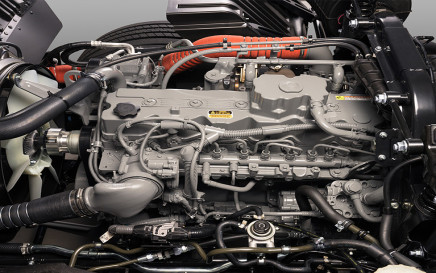 Gray diesel engine with visible pipes, wires, and orange tubing in a vehicle chassis.