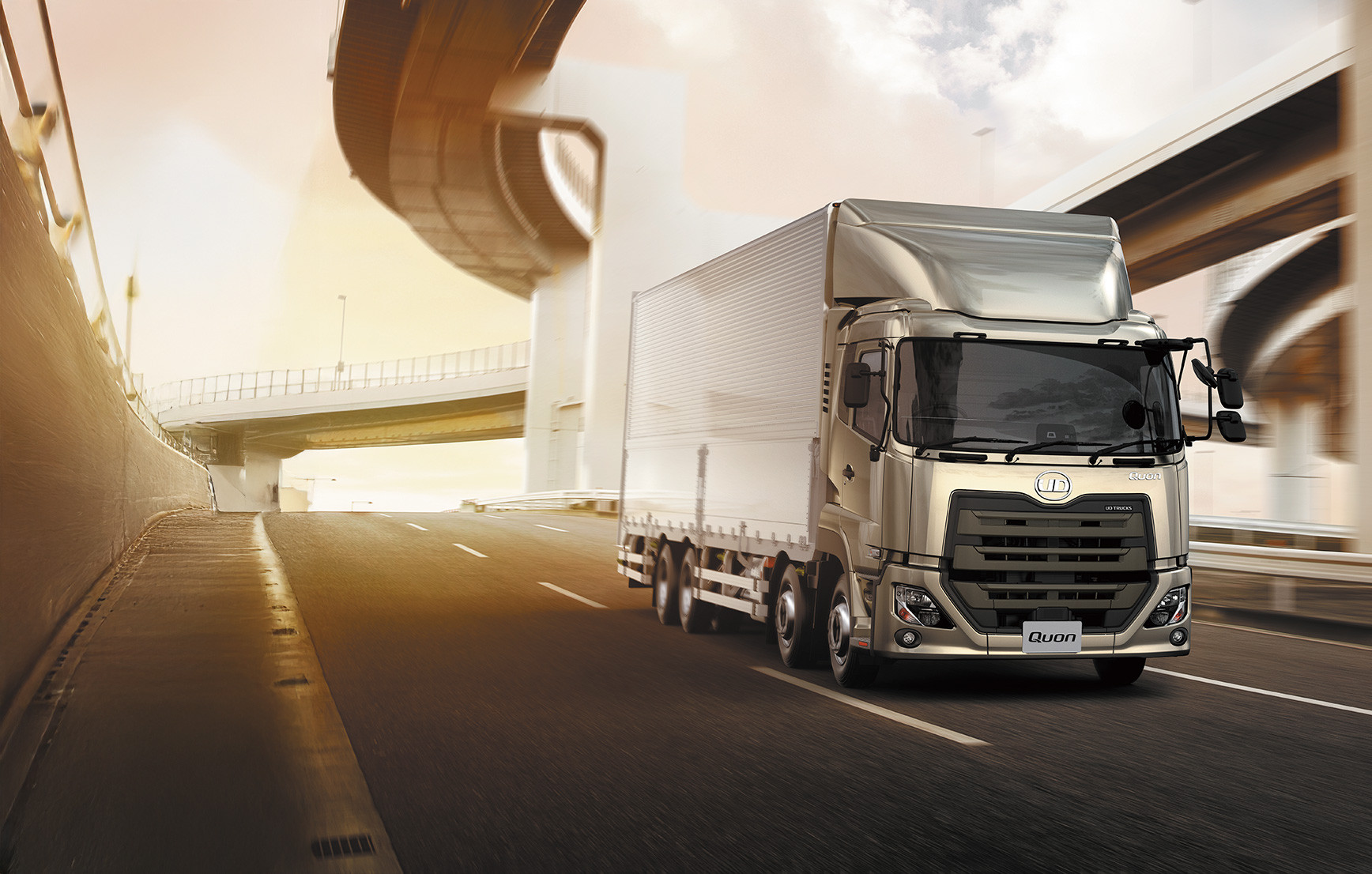 高速道路を走る大型トラック、背景に高架道路と朝焼けの空