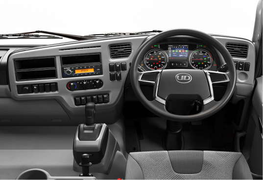 Nội thất cabin xe tải với vô lăng, bảng đồng hồ, các nút điều khiển và cần số.