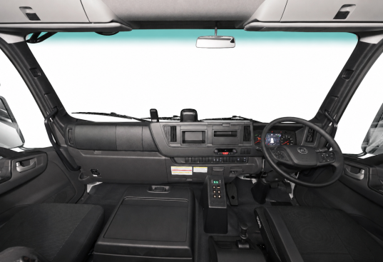 Truck cabin interior with steering wheel, dashboard, and various controls